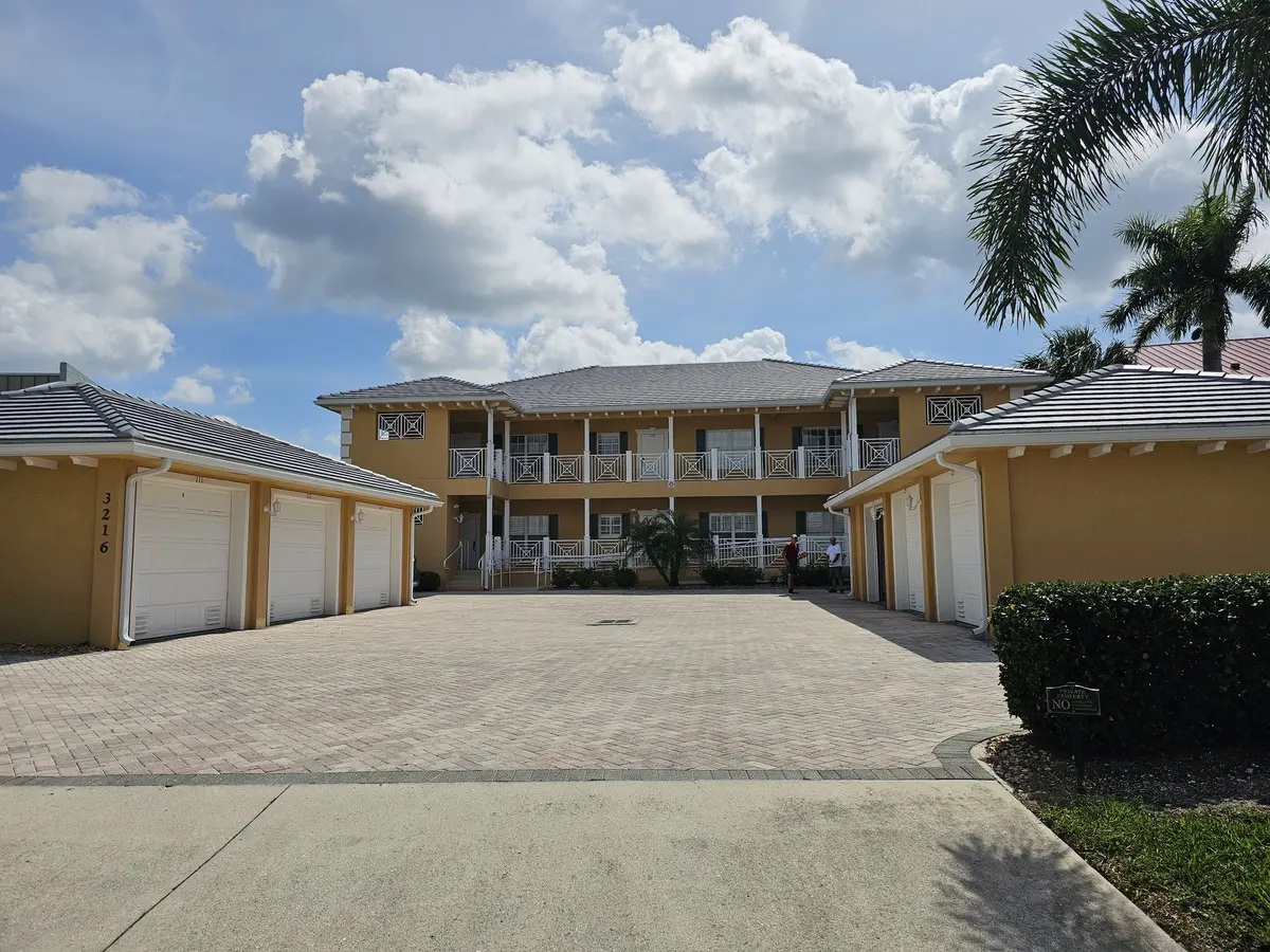 Two-story condo building with new gutters, palm trees and paver courtyard