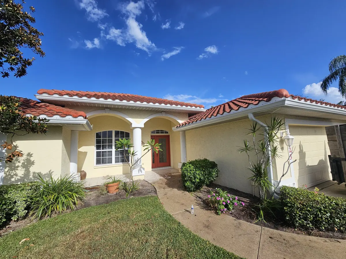 Mediterranean home with tile roof, arched entry, and white seamless gutters